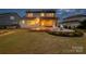 A twilight view of a well-lit backyard featuring a patio with seating and a fire pit at 528 Rock Skip Way, Fort Mill, SC 29708