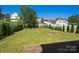 A fenced backyard featuring a fire pit, green lawn, surrounded by manicured evergreen shrubs and mature trees at 726 Centennial St, Gastonia, NC 28056