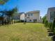 Spacious backyard featuring a lush green lawn, a fire pit, bordered by a privacy fence and manicured shrubs at 726 Centennial St, Gastonia, NC 28056
