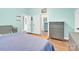 Bedroom features light blue walls, hardwood style floors, bed, gray dresser and a view into another room at 803 N Walnut St, Kannapolis, NC 28081