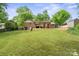Expansive backyard view showcasing the brick house with a covered patio, set against a backdrop of lush trees at 828 N 6Th St, Albemarle, NC 28001