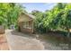 Charming side view of a brick home, surrounded by greenery, featuring a private driveway and outdoor storage shed at 828 N 6Th St, Albemarle, NC 28001