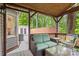 Inviting covered deck features wicker furniture, a ceiling fan, and serene wooded views at 8819 Kishorn Ct, Charlotte, NC 28215