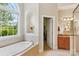 Bright bathroom featuring a soaking tub under a window and a doorway to a walk-in closet at 8905 Landsdowne Ave, Harrisburg, NC 28075