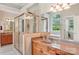 Bathroom featuring a glass-enclosed shower, double vanity, and soaking tub under a large window at 8905 Landsdowne Ave, Harrisburg, NC 28075