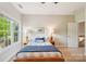 Bright bedroom with a large window, two side tables, and a staircase in the background at 8905 Landsdowne Ave, Harrisburg, NC 28075