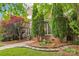Beautifully landscaped front yard with brick accents, mature trees, and manicured garden beds at 8905 Landsdowne Ave, Harrisburg, NC 28075
