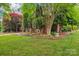 Lovely front yard featuring lush green lawn, garden beds, mature trees and brick exterior at 8905 Landsdowne Ave, Harrisburg, NC 28075