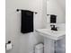 A minimalist bathroom with a pedestal sink, black hardware, and a black towel bar at 9823 Oaklawn Nw Blvd, Huntersville, NC 28078