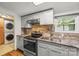A modern kitchen features stainless steel appliances, gray cabinets, a granite countertop and a stacked washer and dryer at 1005 Caldon Dr, Stanley, NC 28164