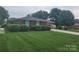Brick home featuring a well-kept lawn, tidy hedges, and a convenient covered parking area at 1165 Mt Moriah Church Rd, China Grove, NC 28023