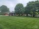 Home on a verdant lawn, framed by mature trees, with a glimpse of the brick facade at 1165 Mt Moriah Church Rd, China Grove, NC 28023