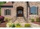 Stunning stone entrance with a detailed dark wood door and intricate iron railings, inviting you home at 1304 Lookout Cir, Waxhaw, NC 28173
