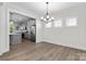 Open-concept dining room with light wood flooring, modern chandelier, and kitchen view at 1308 Stone Marker Dr, Monroe, NC 28112