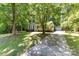 Well-maintained single-story home with a detached garage and a long driveway surrounded by trees at 16320 Peach Grove Ln, Charlotte, NC 28277
