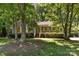 Charming single-story home with a cozy front porch surrounded by lush greenery and mature trees at 16320 Peach Grove Ln, Charlotte, NC 28277