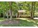 Charming single-story home with a cozy front porch surrounded by lush greenery and mature trees at 16320 Peach Grove Ln, Charlotte, NC 28277