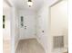 Bright hallway with neutral paint, paneled walls and tiled floors leading to the front door at 16320 Peach Grove Ln, Charlotte, NC 28277