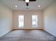 A neutral-toned bedroom featuring plush carpet, a ceiling fan, and natural light from two windows at 1706 Ruben Rd, Monroe, NC 28112