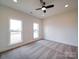 A neutral-toned bedroom featuring carpet flooring, a ceiling fan, and natural light from two windows at 1706 Ruben Rd, Monroe, NC 28112