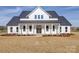 Stunning white farmhouse featuring a charming front porch with classic columns and a double door entrance at 1706 Ruben Rd, Monroe, NC 28112
