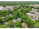 Aerial view of a neighborhood featuring lush green trees, mixed residential and commercial buildings, with city in the distance at 1806 Asbury Hall Ct, Charlotte, NC 28209