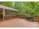 Wooden back deck surrounded by lush greenery and a screened-in porch at 1806 Asbury Hall Ct, Charlotte, NC 28209