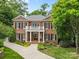 Stately brick home featuring a welcoming front porch with columns and a well-manicured lawn surrounded by lush trees at 1806 Asbury Hall Ct, Charlotte, NC 28209