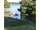 A view of the lake from a lush green lawn with a dock and boat at 209 Woodstream Cir, Mooresville, NC 28117