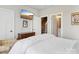A quaint bedroom shows white linens, an arm chair, and an ensuite bath just beyond a door at 2111 Isom St, Charlotte, NC 28208