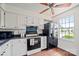 Cozy kitchen featuring white cabinets, black appliances, and a window at 218 Water Oak Dr, Pineville, NC 28134