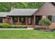 Charming brick home with a cozy front porch framed by wooden pillars and manicured landscaping at 2202 Bearskin Ln, Monroe, NC 28110