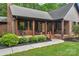 Inviting brick front porch with wood columns, seating, and landscaped garden beds enhance curb appeal at 2202 Bearskin Ln, Monroe, NC 28110