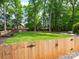 Spacious backyard features a lush lawn, mature trees, and a charming wooden fence at 2329 Wedgewood Dr, Matthews, NC 28104