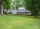 Classic two-story home features a large front porch, lush green lawn, and mature trees providing shade at 2329 Wedgewood Dr, Matthews, NC 28104