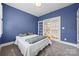 Cozy bedroom with blue walls, plush carpet, and double doors leading to a bright hallway at 2311 Club Rd, Charlotte, NC 28205