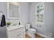 Well-lit half bathroom with white vanity, framed mirror, modern fixtures, and wood flooring at 233 E Waterlynn Rd # B, Mooresville, NC 28117