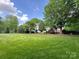 Expansive green lawn, mature trees, and manicured landscaping create a serene backyard oasis at 2556 Howerton Ct, Charlotte, NC 28270