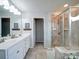 A bright bathroom featuring double sinks, a glass-enclosed shower, and tiled flooring at 4008 Houndscroft Rd, Indian Trail, NC 28079
