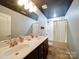 A modern bathroom featuring double sinks, a combination shower and bathtub, and dark-stained cabinetry at 4008 Houndscroft Rd, Indian Trail, NC 28079