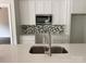 A modern kitchen with white cabinets, stainless steel appliances, a tiled backsplash, and a quartz countertop at 418 W Westview St, Gastonia, NC 28052