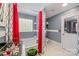 Bright bathroom featuring a soaking tub, white tile floors, red and grey patterned curtains, and glass block window at 636 Sadler Glen Dr, Charlotte, NC 28214