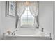 Cozy bathroom highlighting a garden tub with a window and white patterned curtains at 6713 Edwards Farm Ln, Monroe, NC 28110