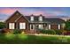 Charming brick home with manicured lawn, dormers, and inviting front porch with decorative shrubbery at 6713 Edwards Farm Ln, Monroe, NC 28110