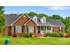 Charming brick home with manicured lawn, dormers, and inviting front porch with decorative shrubbery at 6713 Edwards Farm Ln, Monroe, NC 28110