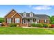 Charming brick home with manicured lawn, dormers, and inviting front porch with decorative shrubbery at 6713 Edwards Farm Ln, Monroe, NC 28110