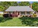 Inviting single-story house with well-kept lawn, cozy front porch, and red front door at 806 Mcgregor Ne Dr, Concord, NC 28025