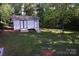 A view of the backyard shed, with a swing set in the grassy and shaded yard at 854 Silver Fox Dr, Concord, NC 28025