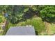 Aerial view of a well maintained home with a large back yard, deck, fire pit, and mature trees at 1011 Master Gunner Ct, Indian Trail, NC 28079