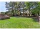 Large backyard with a green lawn, a wooden fence, and mature trees at 1011 Master Gunner Ct, Indian Trail, NC 28079
